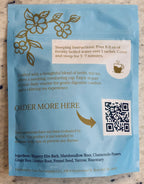 A light blue tea package with gold floral illustrations and black text, including steeping instructions and a QR code, photographed flat against a light neutral surface.